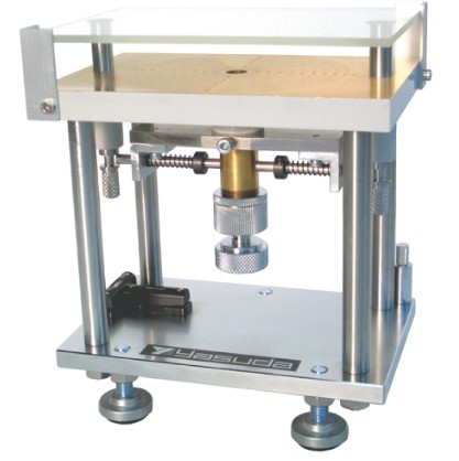 A Yasuda parallel-plate spreadometer — a small benchtop frame with upper and lower plates and a weighted pressing mechanism