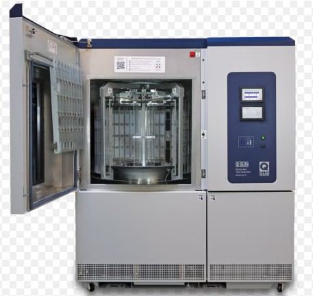 A Q-SUN xenon arc weathering chamber with the door open, showing the rotating sample rack around the lamp